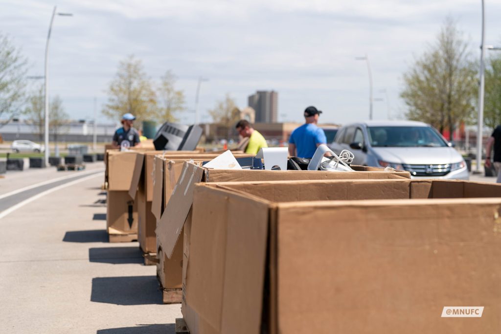 with boxes along a street and people and cars nearby.