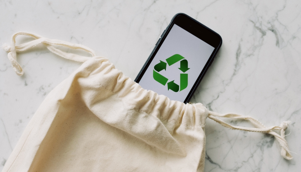 iPhone with recycling image on home screen in a reusable bag.