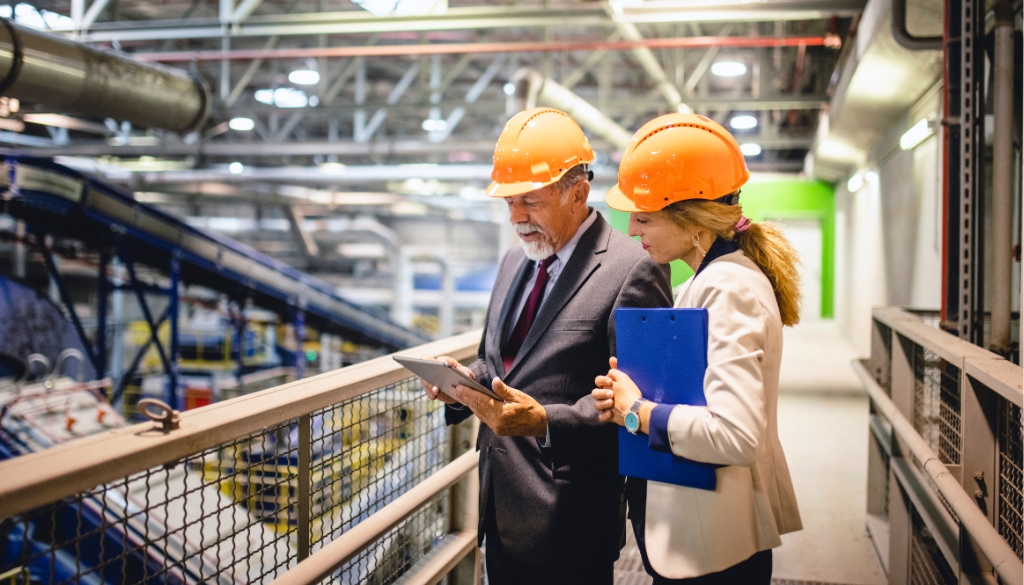 Business partners discussing an ITAD portfolio in an electronics recycling facility.|Spark Blog Logo|Business people reviewing an ITAD plan in a recycling facility.